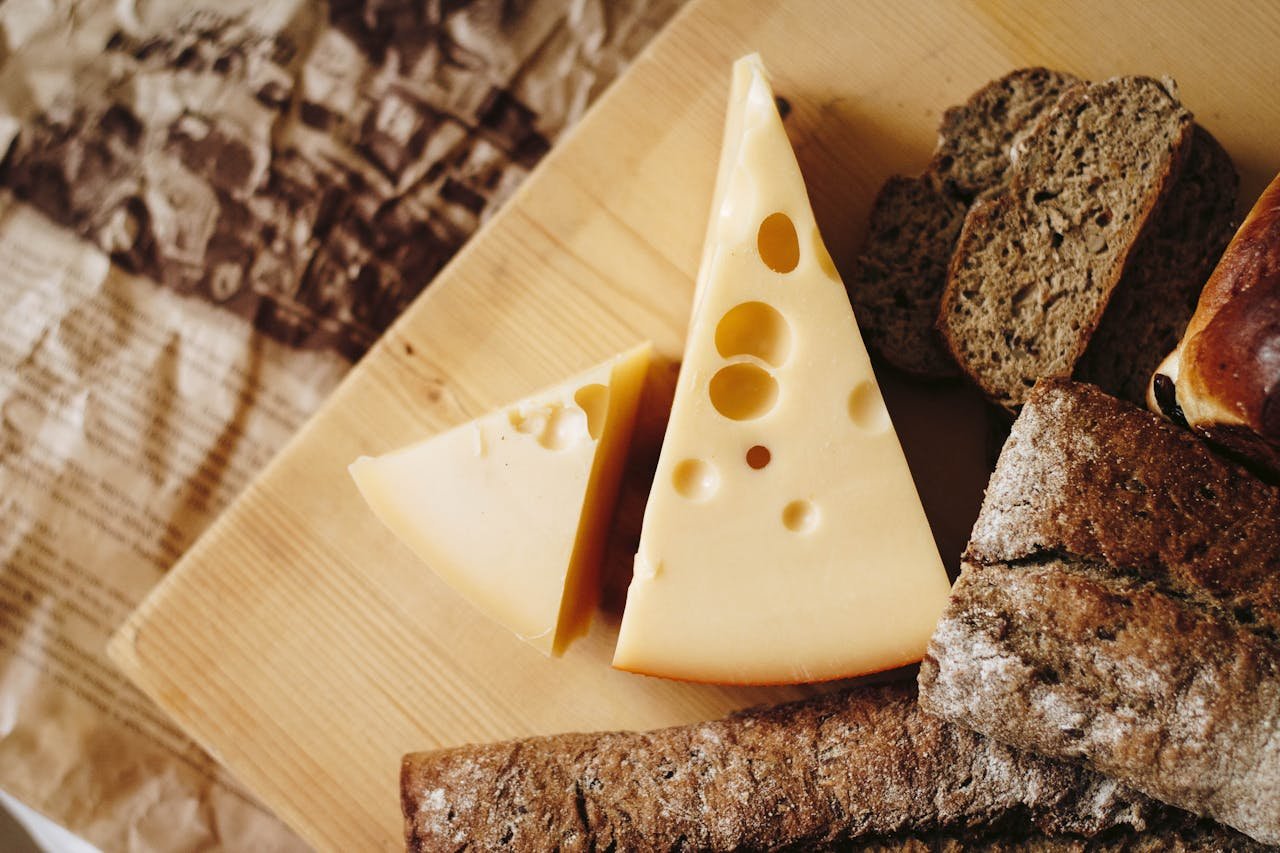 Close-up of cheese and rustic bread on a wooden board, ideal for culinary themes.